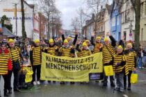 Fußgruppe als Bienen verkleidet, mit Amnesty-Banner beim Karnevalsumzug