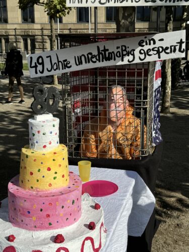 Kunstinstallation zum 80. Geburtstag von Leonard Peltier mit Gefangenenkäfig und Torte aus Papmachee